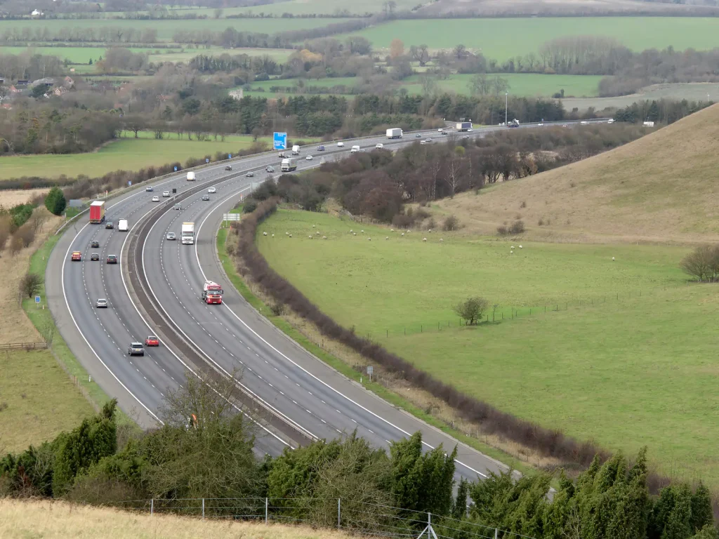 Traffic on the M40 motorway curving through green fields and the Chiltern Hills